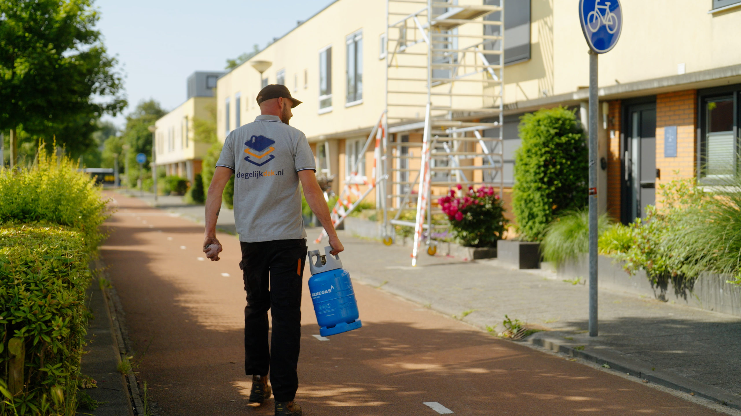 Medewerker van Degelijkdak loopt richting werkplek met gasfles in de hand voor dakrenovatie.