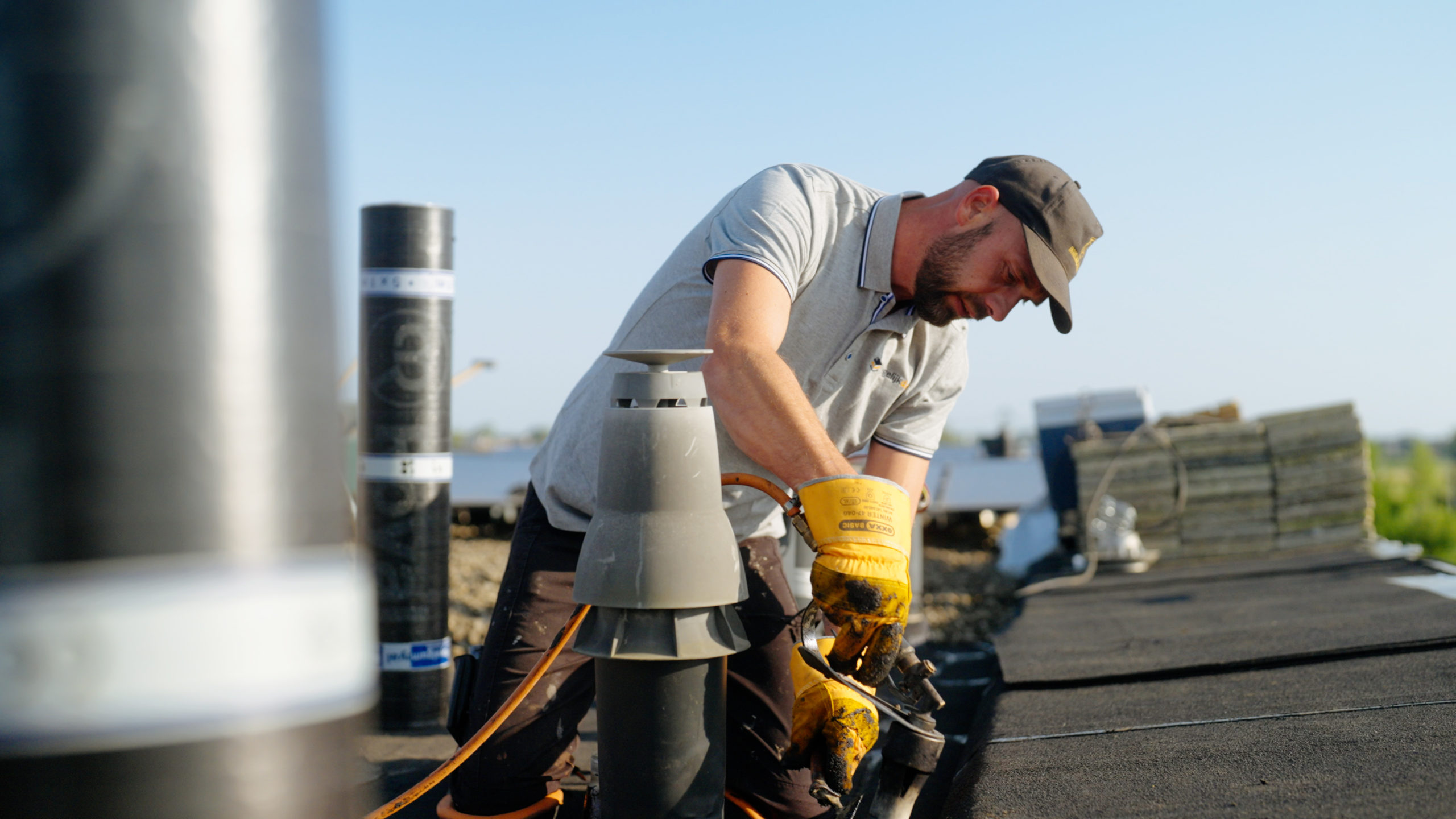 Dakdekker van Degelijkdak werkt aan waterdichte afwerking rond een dakdoorvoer op plat dak.